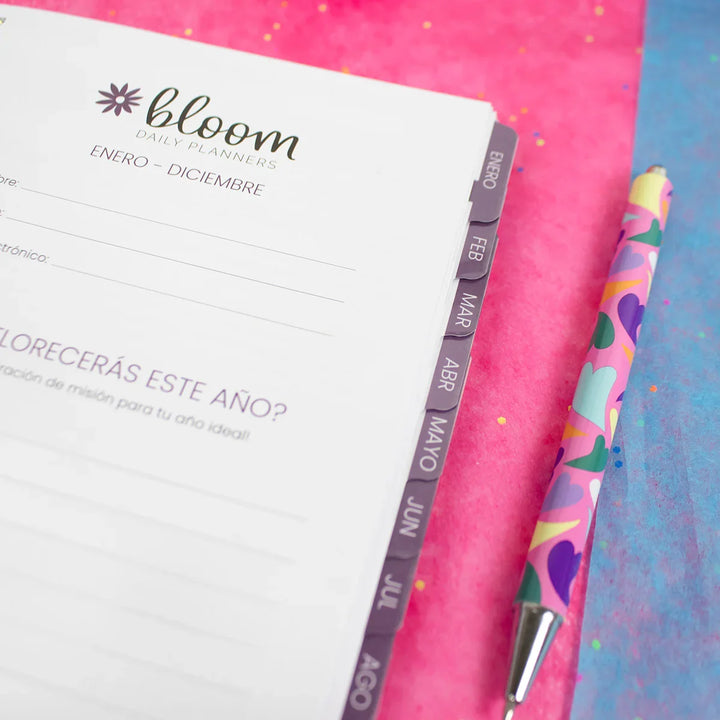 Bloom planner with a colorful pen on a pink and blue background