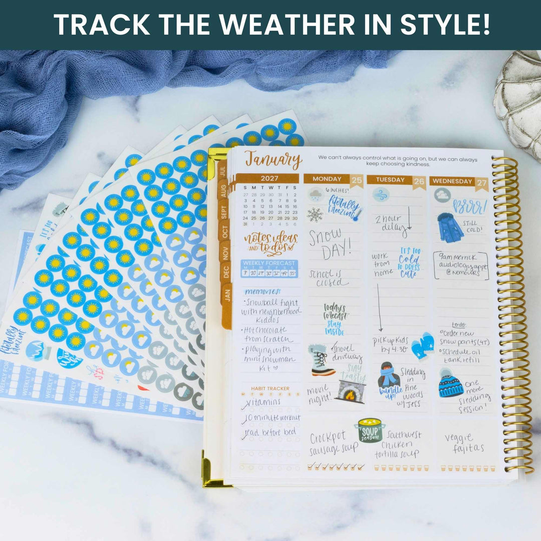 Planner with calendar pages and decorative stickers on a marble surface