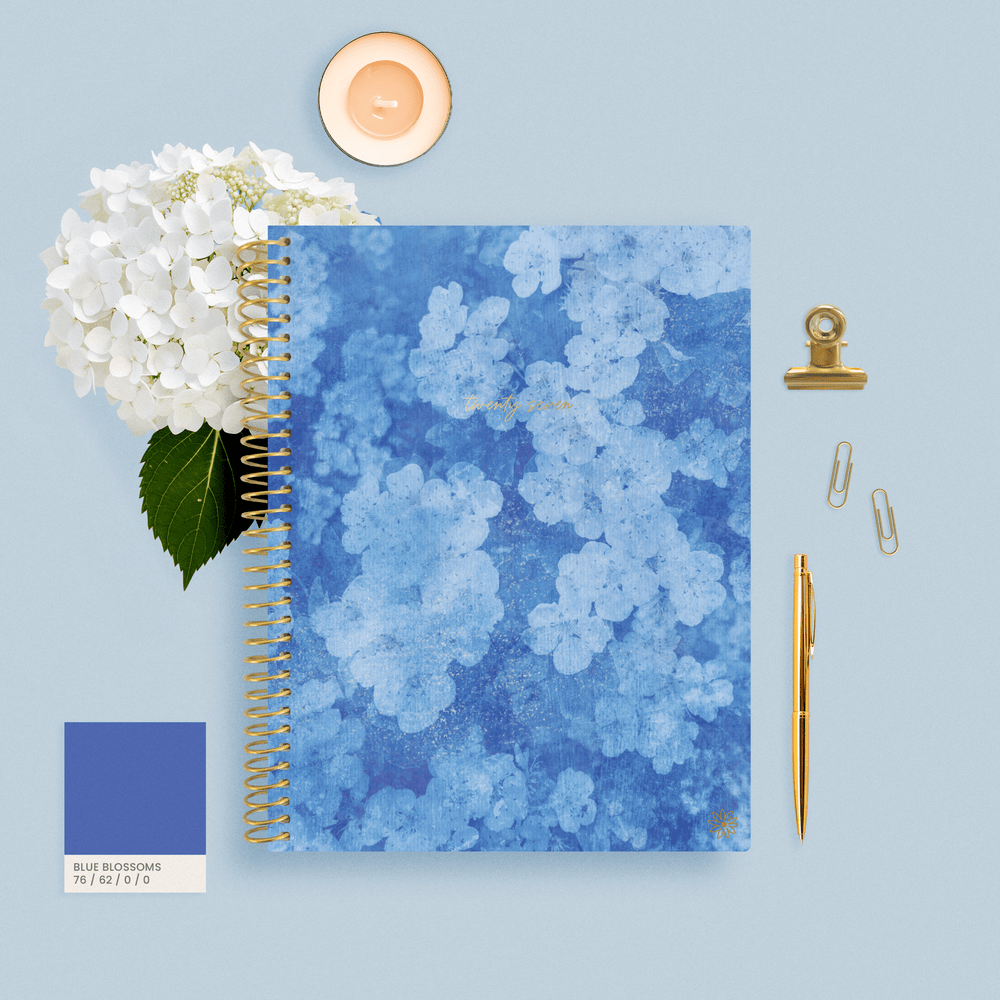 Blue Hydrangea 2027 Planner on a blue background with a flower, candle, pen and paperclips.  - hover
