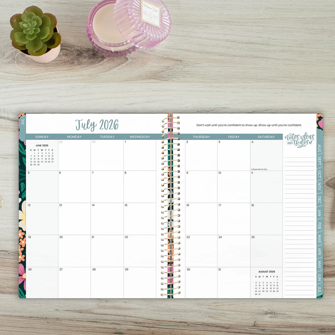 Open planner showing July 2026 on a wooden surface with a plant and candle.