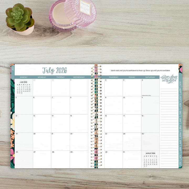 Open planner showing July 2026 on a wooden surface with a plant and candle.