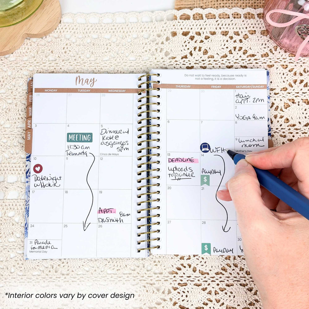 Person writing in a spiral-bound planner on a textured surface