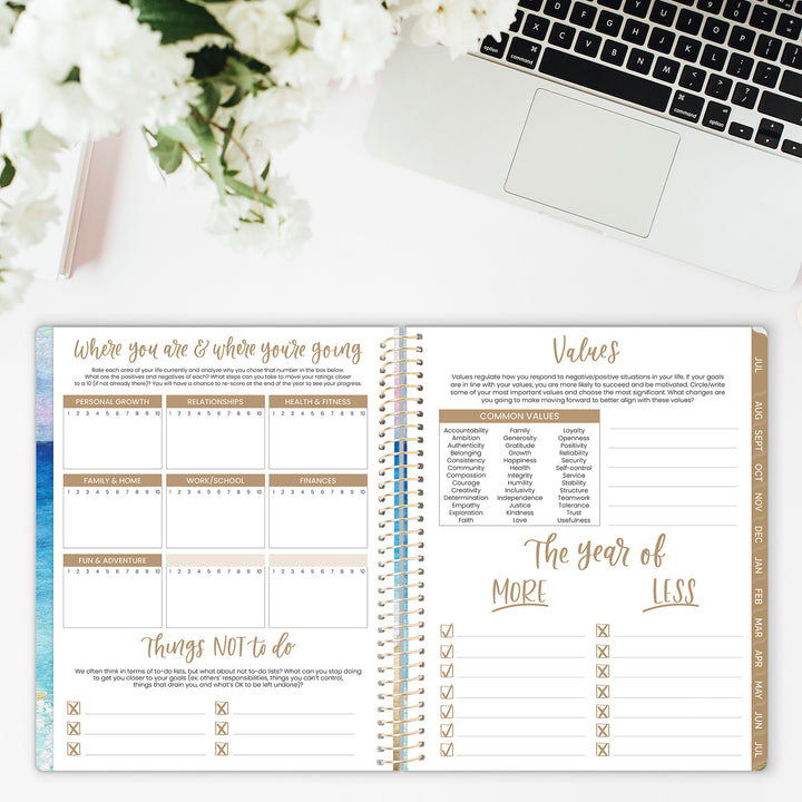 Open planner with spiral binding on a desk with laptop and flowers