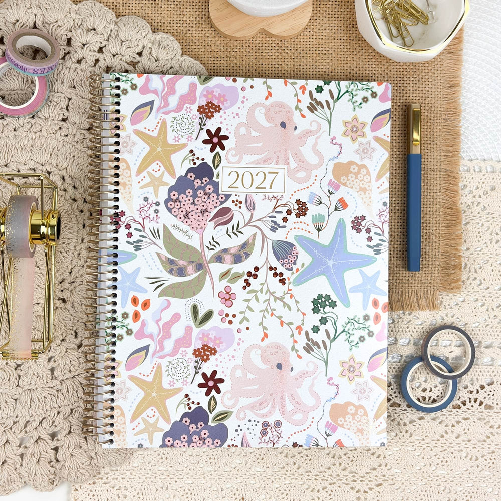 2027 planner on tabletop with colorful seaside floral and starfish cover, spiral binding - hover