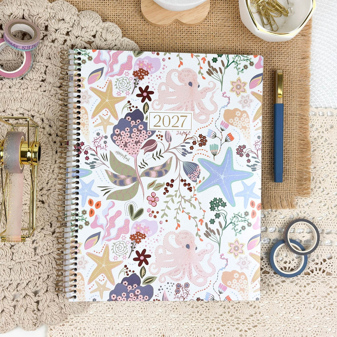 2027 planner on tabletop with colorful seaside floral and starfish cover, spiral binding