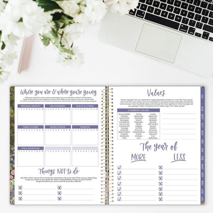 Open planner with a laptop and flowers on a white surface