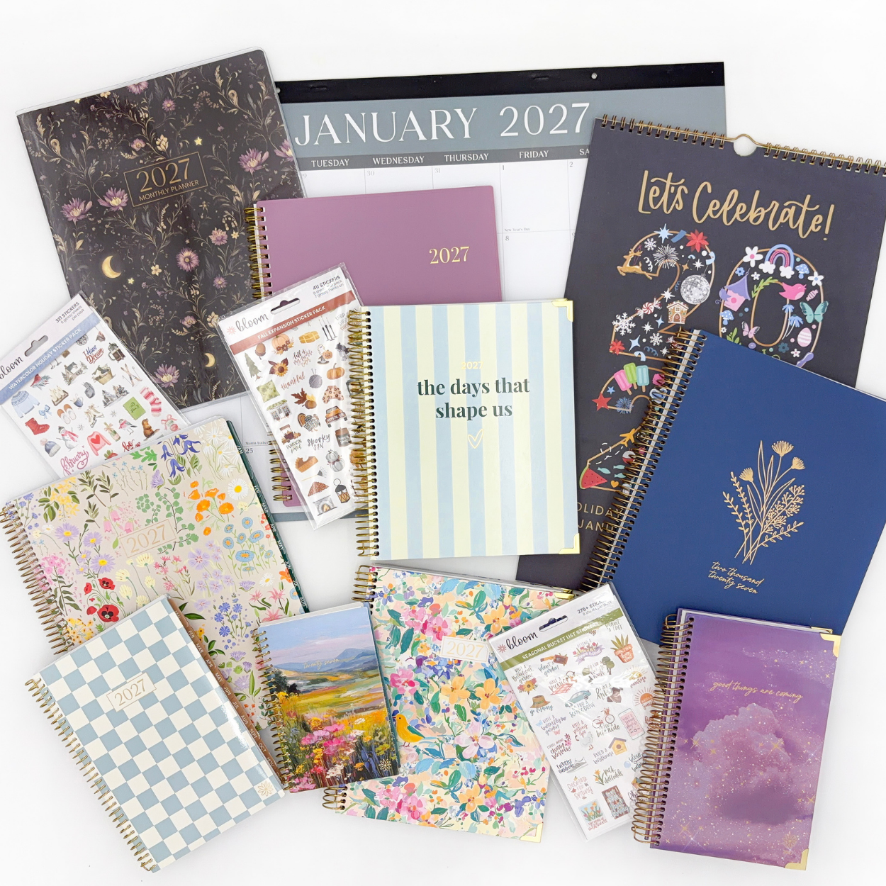 A flat-lay collection of various 2027 planner, notebook, and sticker sets with diverse floral, patterned, and illustrated covers on a clean white background.
