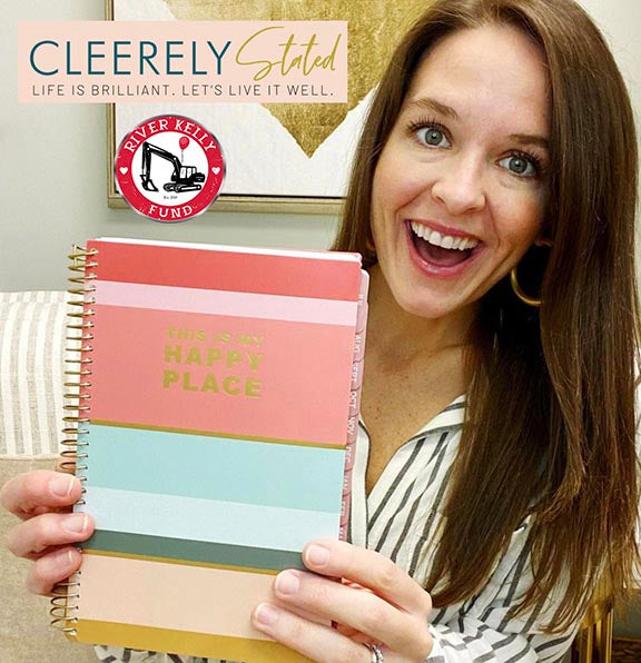 Photo of Cleere, founder of Cleerely Stated, holding a bloom planner featuring her cover design