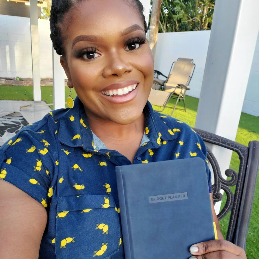 Woman outside holding up a blue Budget Planner.